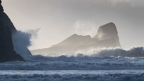 Waves crashing onto the shore with rocks beyond them